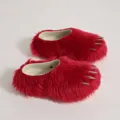 Close-up detail of red faux fur slippers featuring sharp silver decorative animal claws - Red
