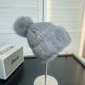 Detail view of a grey winter hat featuring quilted texture and soft fur trim with pom-pom. - One Size / Sapphire Blue
