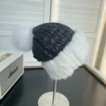 Detailed view of a winter quilted hat featuring white fur trim and plush pom-poms - One Size / White and Black