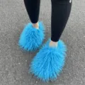 Gedetailleerde close-up van blauwe Mongoolse faux fur slippers op een asfaltgrond - Hemelsblauw