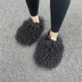Gedetailleerd overzicht van pluizige zwarte Mongoolse bontslippers op een asfaltweg - Zwart