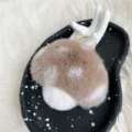 Cute brown and white mushroom plush keychain made of soft rex rabbit fur on a black tray - Camel