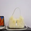 Elegante hellgelbe Kunstpelz-Schultertasche mit verstellbarem Riemen auf dem Tisch. - Gelb