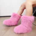 Bottes de neige y2k en fausse fourrure rose vif montrées de profil porté. - Rose vif