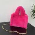 Detalle de un mini bolso de piel sintética rosa con elegante cadena dorada. - Rosa rojo