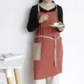 Delantal de algodón naranja quemado con bolsillo beige y tirantes usado por una modelo - Rojo Ladrillo