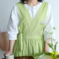 Fresh green cotton V-neck apron with waist tie, shown on model over a white shirt - Plum Green