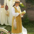 Elegante delantal de algodón amarillo con cuello en V mostrado en un modelo en un jardín - Amarillo jengibre