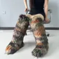Detailed view of colorful Y2K faux fur knee-high snow boots worn by a model in a studio. - Color-Block Raccoon Fur