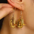 Detailed macro shot of golden western cowboy hat and boot dangle earrings worn on ear - Western Cowboy Boot & Hat Charm Earrings (WG-0505)