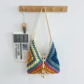 Detailansicht einer bunten Häkeltasche im Granny-Square-Stil an einem hölzernen Wandhaken. - bunt
