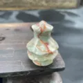 Close up view of a small natural stone Christmas tree carving, delicate crystal decor. - Red Grid Jasper
