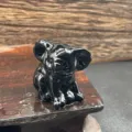 Close-up detail of the hand-carved black crystal koala animal figurine, natural gemstone display. - Obsidian