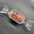 Nahaufnahme der bonbonförmigen Glasflasche mit roten Kristallsplittern als Dekoration. - Roter Achat