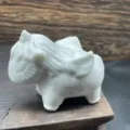 Close-up detail of white crystal unicorn carving, smooth polished gemstone finish texture. - White Turquoise