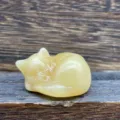 Gros plan d'une sculpture de chat endormi en cristal jaune sculpté à la main. - Stéatite Dorée