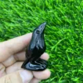 Detail view of hand carved black crystal raven gemstone sculpture showing smooth polished texture. - Obsidian