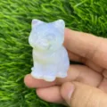 Close-up detail view of a cute sitting cat crystal figurine carved from smooth opalite stone. - Opal