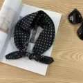 Detail view of a vintage black polka dot scarf styled on a magazine with sunglasses. - Classic Black White Polka Dot