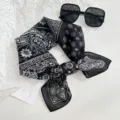 Black and white paisley pattern square scarf detail view with stylish sunglasses flat lay. - Paisley Floral / Black