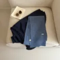 Detailed view of the cozy blue knitted scarf styled with a dark top and rustic book props. - Denim Blue
