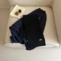 Detailed view of cozy dark blue sweatshirt and black knit scarf styled on white chair. - Classic Black