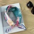Close-up detail shot of a vintage floral print square neckerchief styled on a wooden tabletop. - Picture #15