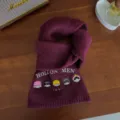 Close-up detail of warm burgundy knit wool scarf with cute cartoon character embroidery. - Wine Red