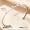 Brazalete abierto de acero inoxidable con pequeñas esferas diseño minimalista para mujer. - Plateado con tres cuentas
