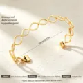 Goldfarbenes offenes Edelstahlarmband mit einem modernen wellenförmigen Design für Damen - Gold Runde Textur