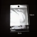 Nahaufnahme Detail eines silbernen Folien-Schmuckverpackungsbeutels mit Aufhängeloch. - Selbstklebender Verpackungsbeutel / 10x8cm