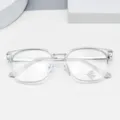 Clear frame glasses detail shot showing transparent optical lens with blue light blocking sticker. - Clear White