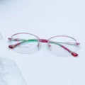 Close-up detail of stylish pink metal semi-rimless eyeglasses frame, elegant and modern. - Pink