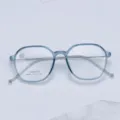 Primer plano detallado de la montura de gafas azul transparente poligonal con patillas metálicas. - Azul transparente