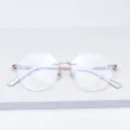 Gros plan détaillé de lunettes polygonales sans monture avec pont doré et branches pailletées. - Or rose