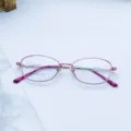 Close-up detail of the pink metal full-frame eyeglasses, showcasing the oval frame and slim temples. - Pink / Plain
