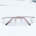 Minimalist square rimless eyeglasses frame with brown titanium temples and clear demo lenses. - Coffee