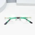 Detailansicht der leichten rahmenlosen optischen Brille mit goldener Metallbrücke und grünen Bügeln. - Glänzendes Gold