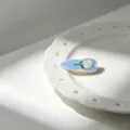 Detailed view of the French retro blue enamel hair clip featuring a white rose design. - White