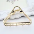 Close-up detail of minimal gold triangle metal hair claw clip for women styling accessory. - Rounded Triangle
