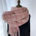 Vue rapprochée détaillée de l'écharpe en tricot à carreaux roses avec de belles franges. - Rose