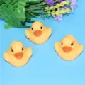 Close-up detail view of floating glowing yellow bath duck toy in water playing scene. - Yellow