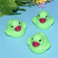 Close-up detail view of cute LED glowing bath duck toys floating on water for children. - Glowing Green Ducks