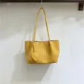 Close up of yellow soft woven leather underarm bag detail with cute heart charm accessory. - Turmeric