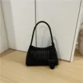Black woven leather shoulder bag, chic underarm baguette style with elegant intrecciato texture detail. - Black