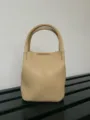 Vista dettagliata di una mini borsa a secchiello in pelle beige, elegante e compatta per l'uso. - Giallo