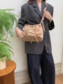 Detail view of the beige ruched shoulder bag with chic drawstring bowknot design and strap. - Apricot