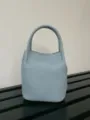 Vista dettagliata di una mini borsa a secchiello in pelle azzurra con finitura strutturata. - Blu