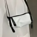 White cylindrical nylon crossbody bag detail, minimalist design with black strap. - 181 Waterproof White