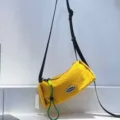 Detail view of bright yellow cylindrical crossbody bag showing texture and black strap - Yellow